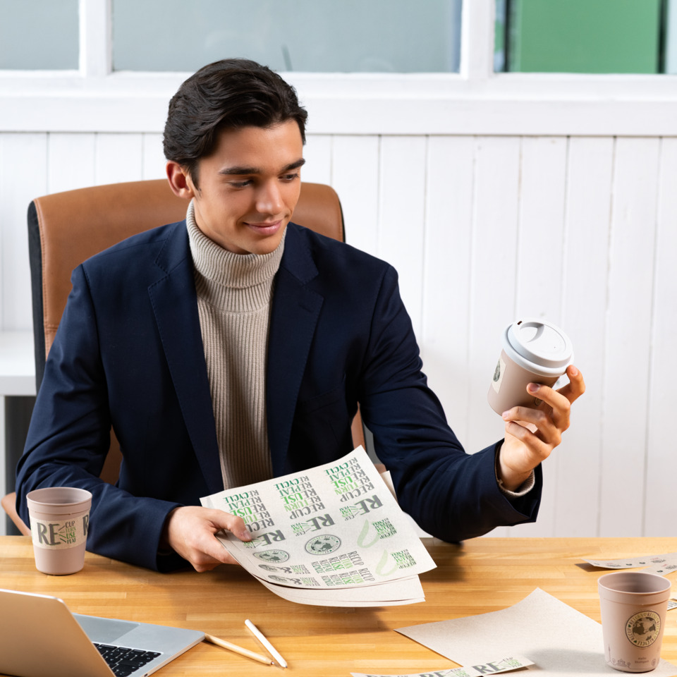 Mann mit Kaffee, Schreibtisch im Büro, Rollkragenpullover, Blazer, To-Go-Becher, Anzug, Rollkragenpullover, Kaffeemappe, Geldscheine, Kaffeebecher
