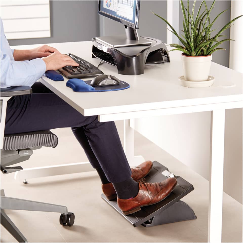 ergonomischer schreibtisch, büro einrichtung, fußstütze, fußpedal, braune lederschuhe
